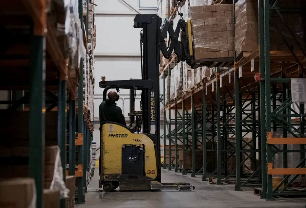 A forklift moving palletised cargo in a logistics warehouse